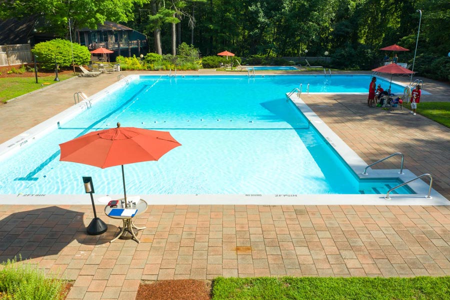 Beautiful blue pool with orange umbrellas taken care of by a property management company